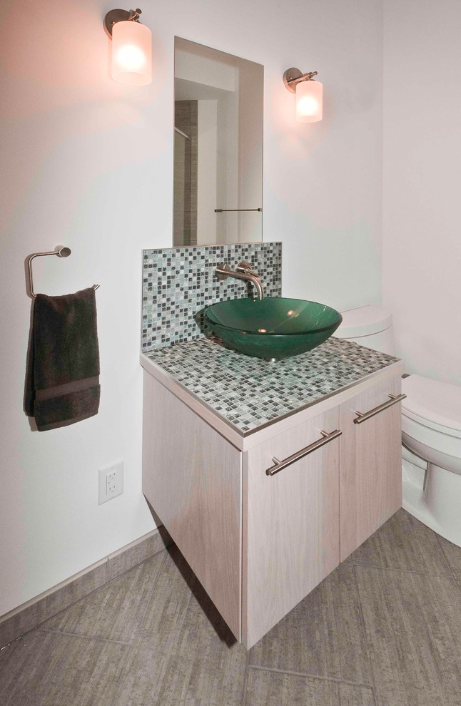 Inspiration for a contemporary multicolored tile and mosaic tile ceramic tile bathroom remodel in Wichita with flat-panel cabinets, light wood cabinets, a one-piece toilet, white walls, a vessel sink and tile countertops