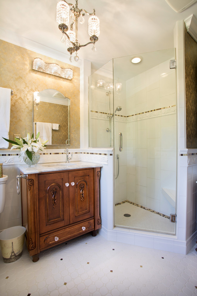 Aménagement d'une salle de bain principale classique en bois foncé avec un lavabo encastré, un placard en trompe-l'oeil, un plan de toilette en marbre, une douche d'angle, WC à poser, un carrelage blanc, des carreaux de céramique, un mur jaune et un sol en carrelage de céramique.