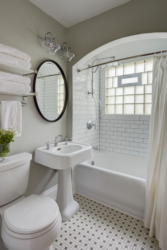 This is an example of a small victorian bathroom in Milwaukee with shaker cabinets, white cabinets, an alcove bath, an alcove shower, a two-piece toilet, white tiles, grey walls, ceramic flooring and a pedestal sink.
