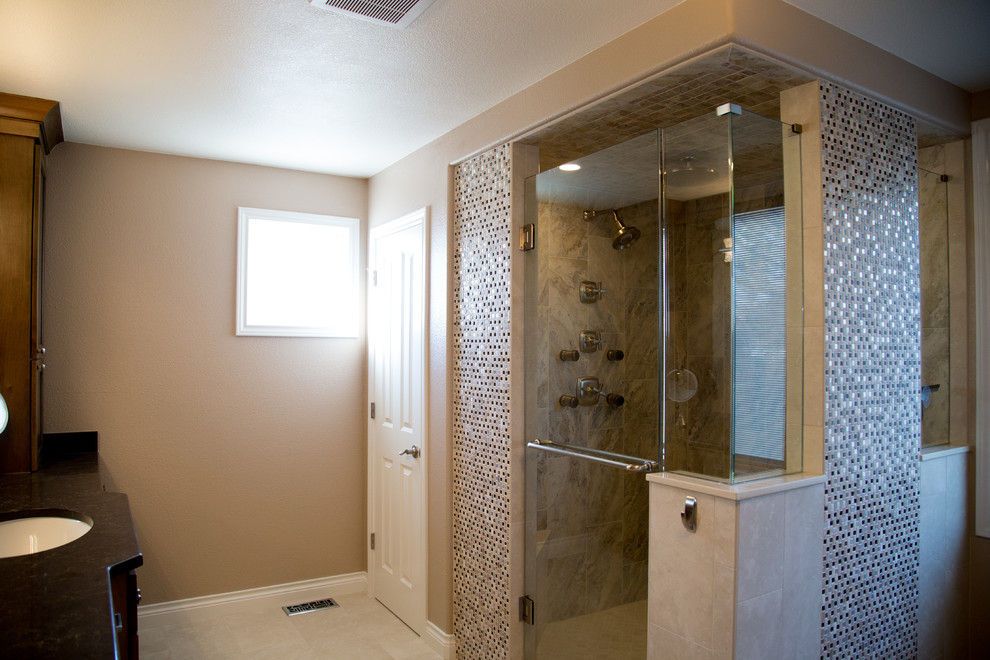 Foto på ett stort vintage en-suite badrum, med luckor med infälld panel, bruna skåp, en dubbeldusch, beige kakel, porslinskakel, beige väggar, klinkergolv i porslin, ett undermonterad handfat och träbänkskiva