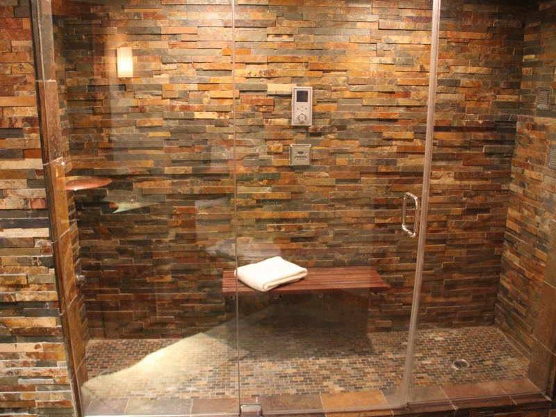 Large classic ensuite bathroom in New York with an alcove shower, beige tiles, brown tiles, stone tiles, porcelain flooring, a submerged sink, solid surface worktops, brown floors and a hinged door.