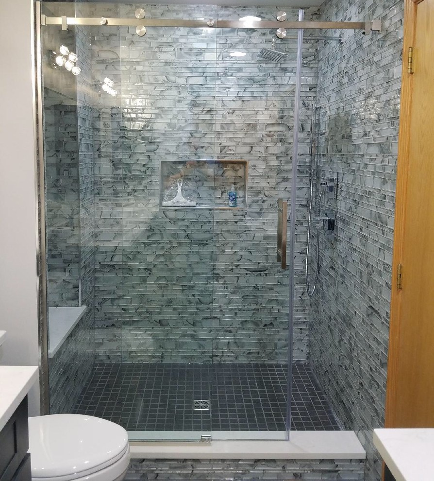 Photo of a small contemporary shower room bathroom in Chicago with shaker cabinets, dark wood cabinets, an alcove shower, a one-piece toilet, grey tiles, glass tiles, white walls, a submerged sink, engineered stone worktops, grey floors, a sliding door and white worktops.
