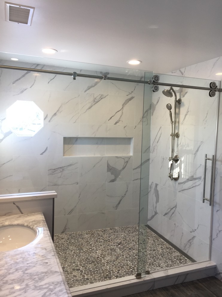 Inredning av ett modernt mellanstort grå grått badrum med dusch, med en dusch i en alkov, grå kakel, vit kakel, marmorkakel, vita väggar, mörkt trägolv, marmorbänkskiva, brunt golv och dusch med skjutdörr