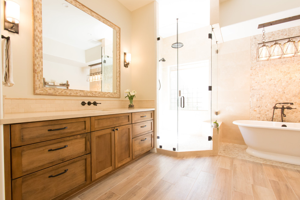 This is an example of a medium sized mediterranean ensuite bathroom in Phoenix with shaker cabinets, medium wood cabinets, a freestanding bath, a one-piece toilet, beige tiles, travertine tiles, beige walls, porcelain flooring, a submerged sink, marble worktops, beige floors and a hinged door.