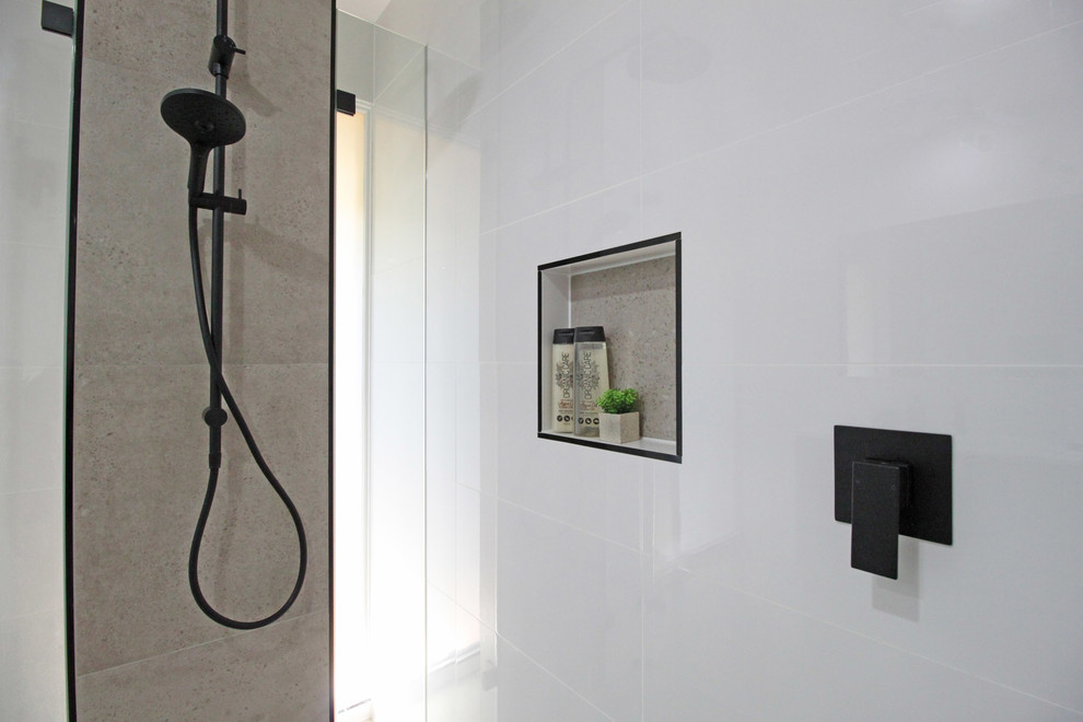 This is an example of a medium sized modern ensuite bathroom in Brisbane with flat-panel cabinets, dark wood cabinets, a walk-in shower, a two-piece toilet, white tiles, ceramic tiles, white walls, porcelain flooring, a submerged sink, engineered stone worktops, beige floors, an open shower and white worktops.