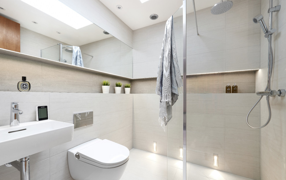 Cette image montre une petite salle d'eau design avec un espace douche bain, WC suspendus, un carrelage gris, des carreaux de porcelaine, un mur gris, un sol en carrelage de porcelaine, un lavabo suspendu, un sol gris et aucune cabine.