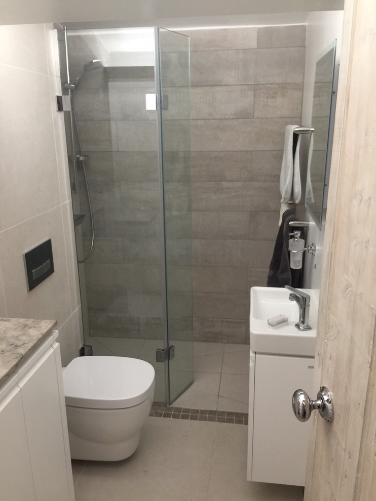 Inspiration for a small contemporary shower room bathroom in Wiltshire with flat-panel cabinets, white cabinets, limestone worktops, a wall mounted toilet, beige tiles, porcelain tiles, beige walls, porcelain flooring, a wall-mounted sink and a corner shower.