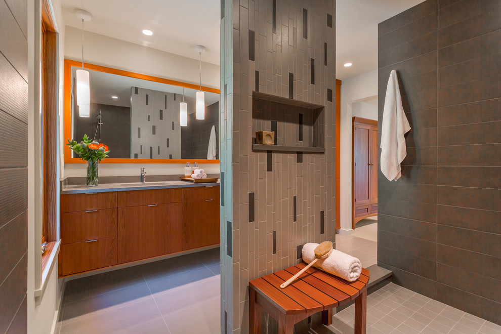 Inredning av ett modernt stort en-suite badrum, med släta luckor, skåp i mellenmörkt trä, en öppen dusch, grå kakel, mosaik, ett undermonterad handfat, bänkskiva i kvarts, en toalettstol med separat cisternkåpa, vita väggar, klinkergolv i porslin och med dusch som är öppen