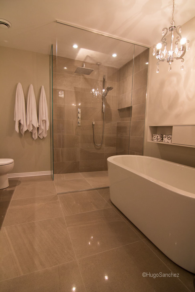 This is an example of a medium sized modern ensuite bathroom in Montreal with a submerged sink, flat-panel cabinets, white cabinets, quartz worktops, a freestanding bath, a built-in shower, a one-piece toilet, grey tiles, porcelain tiles, white walls and porcelain flooring.
