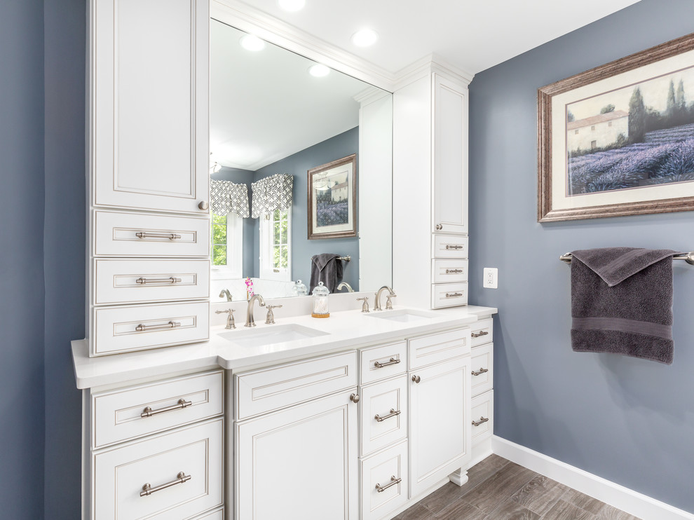 Inspiration for a mid-sized transitional master ceramic tile and brown floor bathroom remodel in DC Metro with beaded inset cabinets, white cabinets, a two-piece toilet, blue walls, an undermount sink, quartzite countertops, a hinged shower door and white countertops
