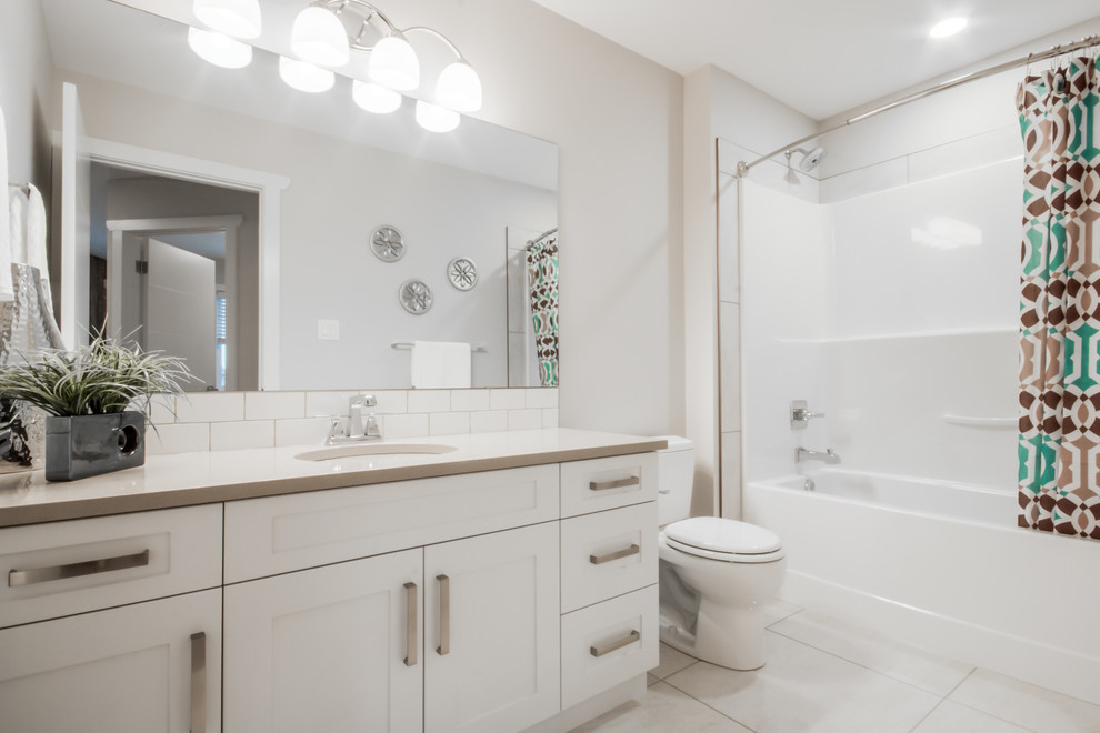 Bathroom - mid-sized contemporary master white tile and porcelain tile porcelain tile bathroom idea in Calgary with shaker cabinets, white cabinets, a one-piece toilet, white walls, an undermount sink and solid surface countertops