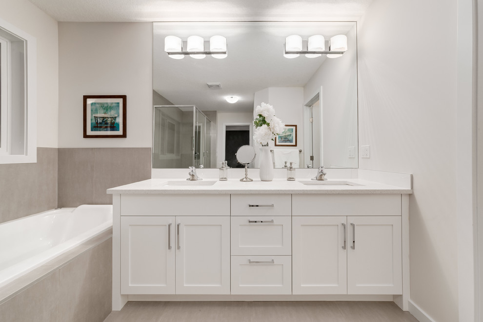Design ideas for a medium sized contemporary ensuite bathroom in Calgary with shaker cabinets, white cabinets, a built-in bath, a corner shower, a two-piece toilet, grey tiles, ceramic tiles, beige walls, ceramic flooring, a built-in sink and engineered stone worktops.