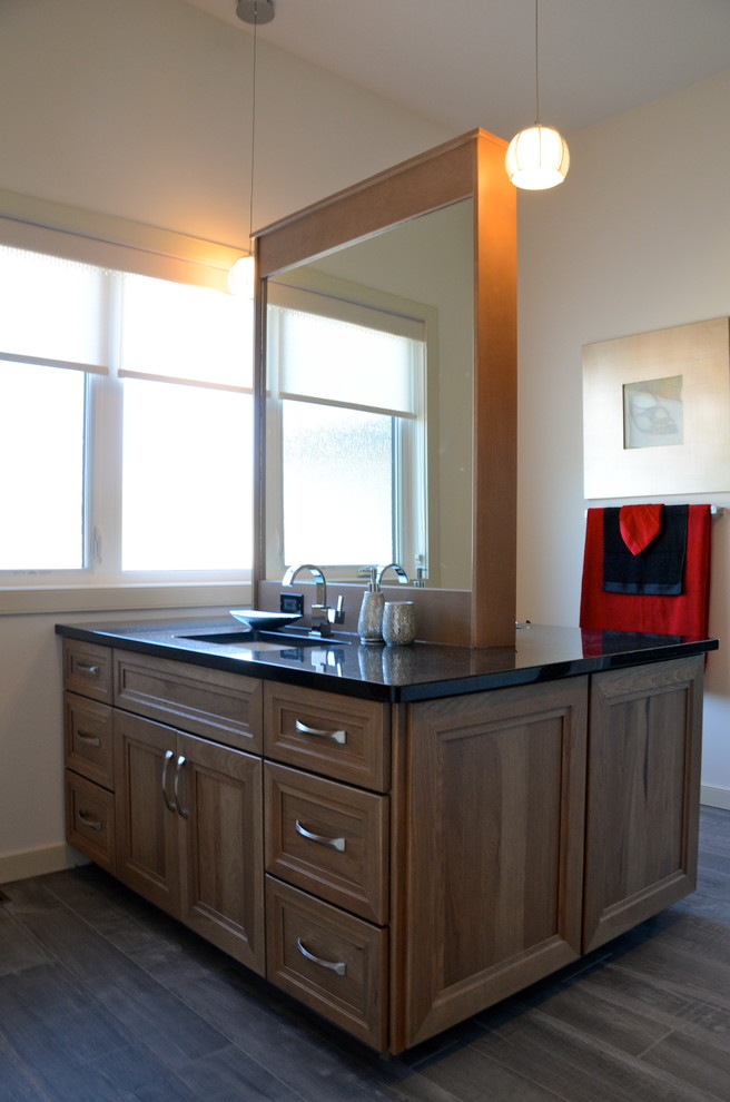 Cette image montre une salle de bain traditionnelle en bois brun avec un lavabo encastré, un placard à porte plane et un plan de toilette en granite.