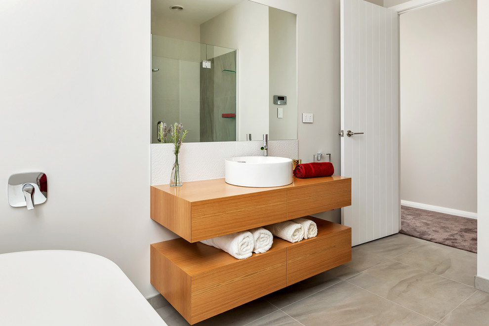 Esempio di una grande stanza da bagno contemporanea con ante in legno scuro, vasca freestanding, piastrelle beige, piastrelle in pietra e top in legno