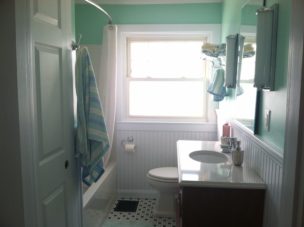 Foto på ett litet lantligt badrum, med ett undermonterad handfat, skåp i mörkt trä, bänkskiva i kvarts, ett badkar i en alkov, en toalettstol med separat cisternkåpa, vit kakel, gröna väggar och klinkergolv i keramik