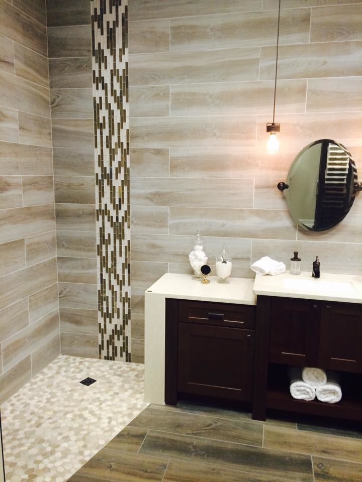 Bild på ett lantligt badrum, med luckor med infälld panel, skåp i mörkt trä, en kantlös dusch, grå kakel, porslinskakel, klinkergolv i småsten, ett undermonterad handfat och bänkskiva i kvarts