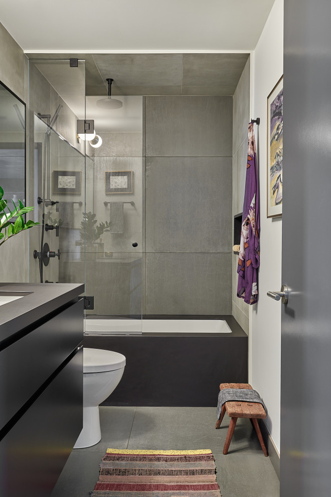 Пример оригинального дизайна: ванная комната среднего размера в стиле модернизм с плоскими фасадами, черными фасадами, накладной ванной, душем над ванной, унитазом-моноблоком, белой плиткой, керамогранитной плиткой, серыми стенами, полом из керамогранита, душевой кабиной, накладной раковиной, столешницей из искусственного кварца, серым полом, душем с распашными дверями и черной столешницей
