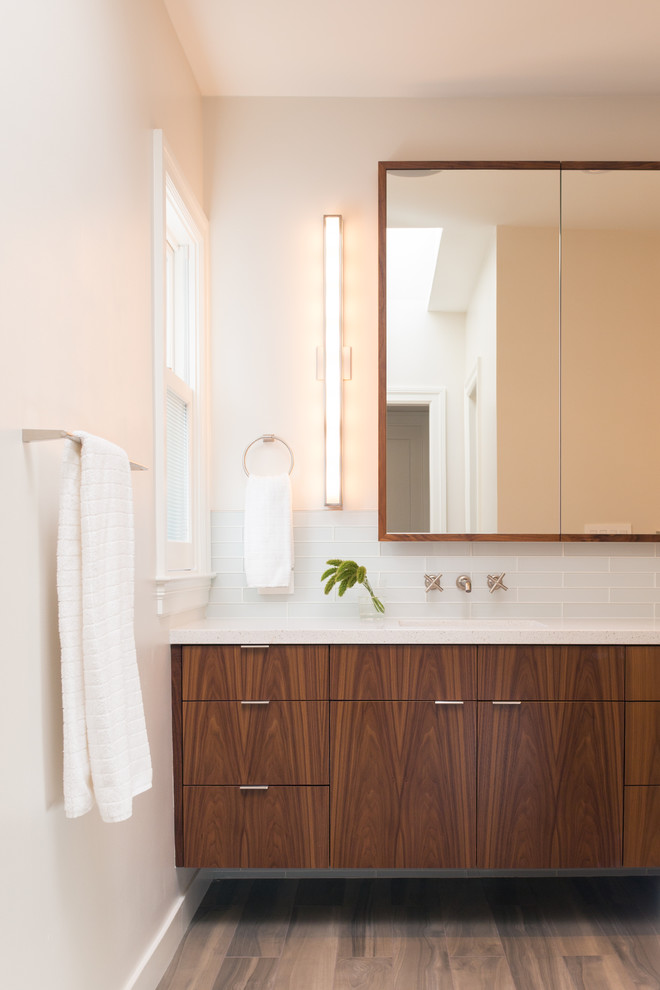 Imagen de cuarto de baño actual con armarios con paneles lisos, puertas de armario de madera en tonos medios, baldosas y/o azulejos blancos y baldosas y/o azulejos de vidrio
