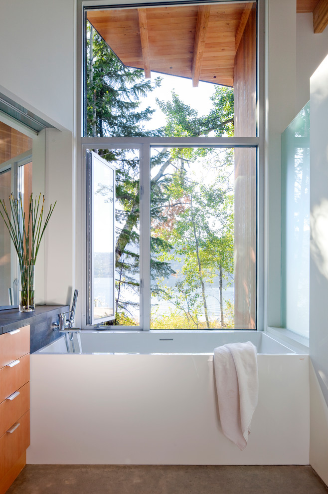 Пример оригинального дизайна: ванная комната в стиле модернизм с плоскими фасадами, фасадами цвета дерева среднего тона и отдельно стоящей ванной