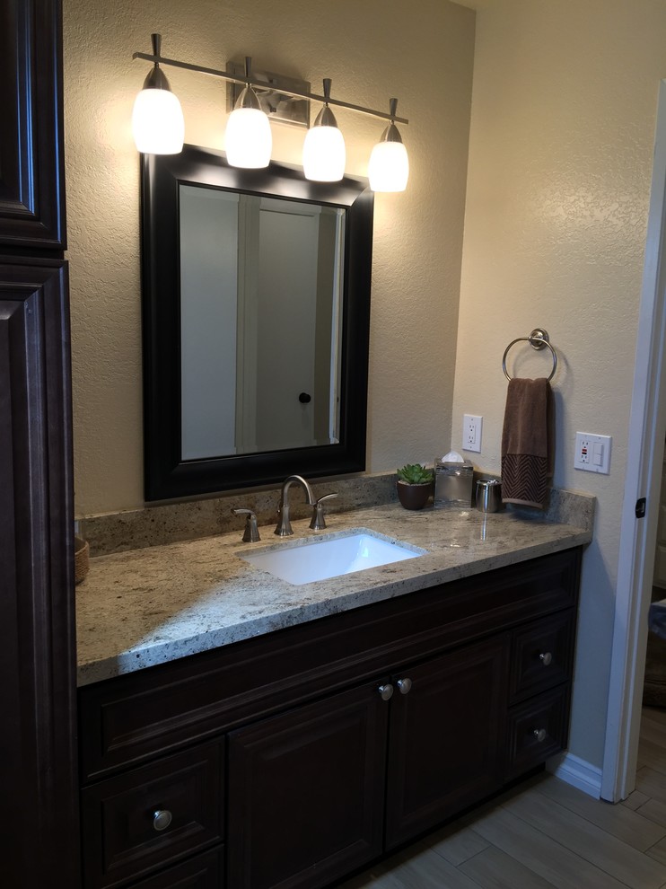 Example of a mid-sized transitional kids' beige tile and porcelain tile porcelain tile bathroom design in Los Angeles with an undermount sink, raised-panel cabinets, dark wood cabinets, granite countertops, a two-piece toilet and beige walls