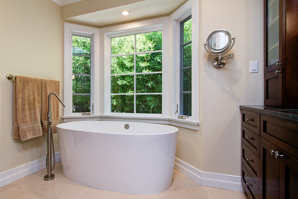 Idee per una stanza da bagno classica con ante in stile shaker, vasca freestanding, pareti beige, pavimento in gres porcellanato, top in granito e top nero