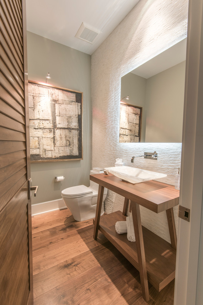 Inspiration pour une salle d'eau minimaliste en bois brun de taille moyenne avec une vasque, un placard sans porte, un plan de toilette en bois, WC à poser, un carrelage blanc, des carreaux de céramique, un mur gris et un sol en bois brun.