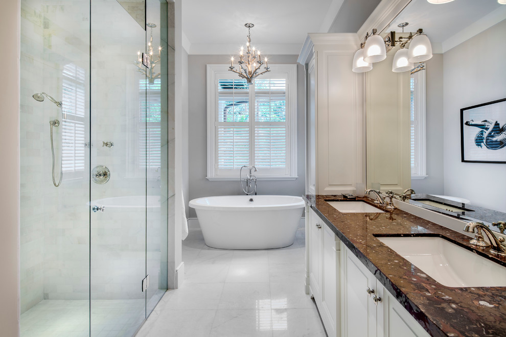 Exempel på ett stort klassiskt brun brunt en-suite badrum, med ett undermonterad handfat, luckor med infälld panel, vita skåp, granitbänkskiva, ett fristående badkar, en dusch i en alkov, en toalettstol med hel cisternkåpa, grå kakel, stenkakel, grå väggar och marmorgolv