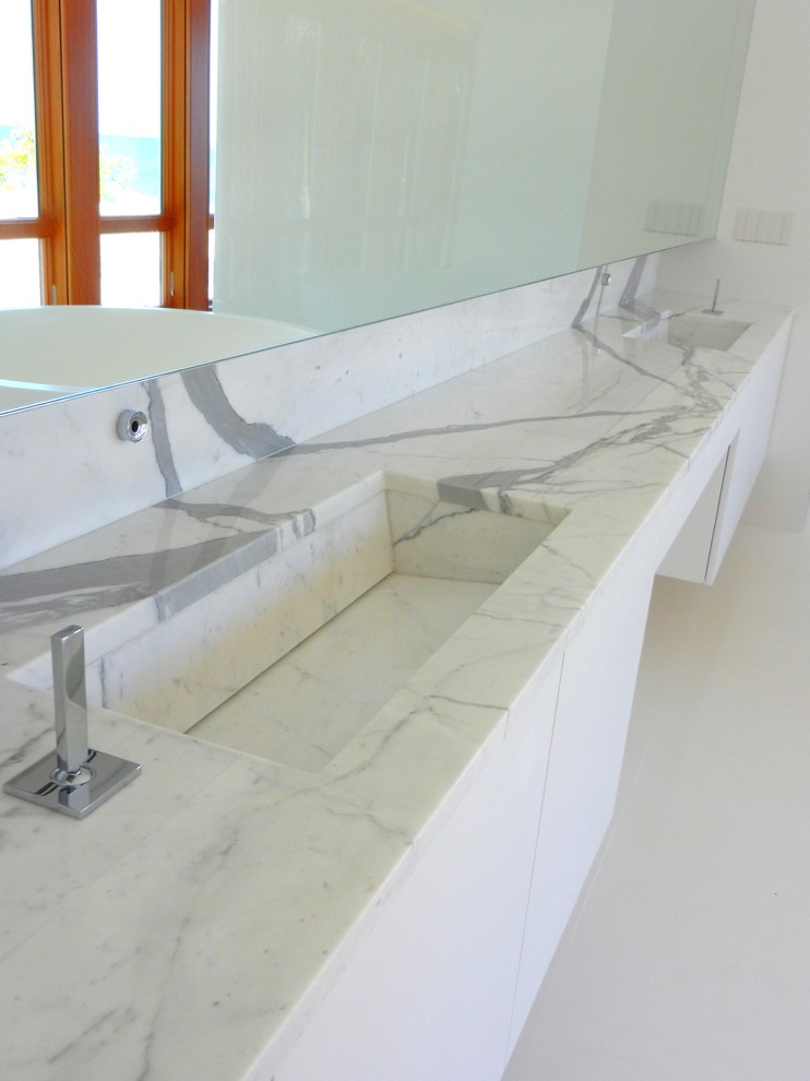Modelo de cuarto de baño principal actual grande con armarios con paneles lisos, puertas de armario blancas y encimera de mármol