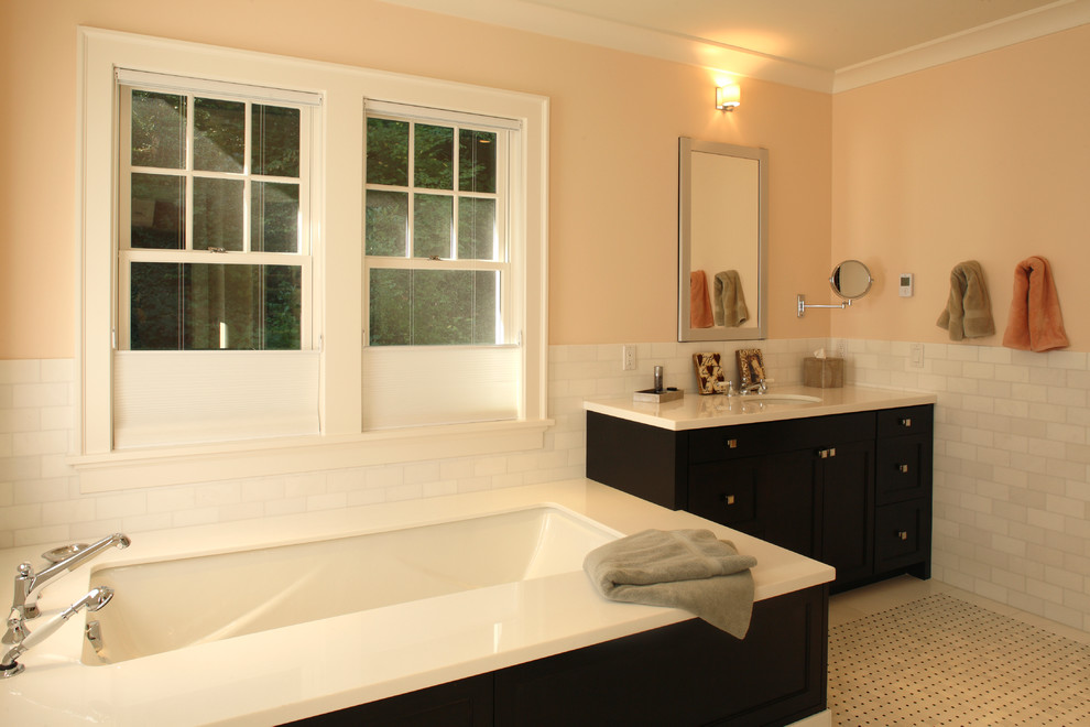 Example of a large classic kids' white tile and subway tile porcelain tile drop-in bathtub design in Portland with black cabinets, orange walls, an undermount sink and solid surface countertops