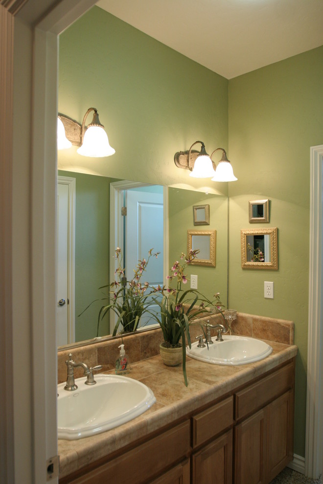 Exempel på ett mellanstort klassiskt badrum med dusch, med ett nedsänkt handfat, luckor med infälld panel, skåp i ljust trä, kaklad bänkskiva, en dusch/badkar-kombination, en toalettstol med hel cisternkåpa, beige kakel, keramikplattor, gröna väggar och klinkergolv i keramik