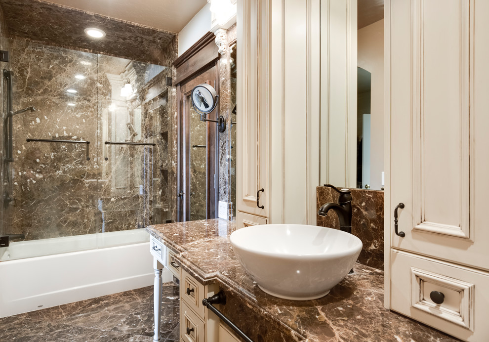 Bathroom - small traditional master brown tile and marble tile marble floor and brown floor bathroom idea in Salt Lake City with recessed-panel cabinets, distressed cabinets, a bidet, beige walls, a vessel sink, marble countertops and brown countertops