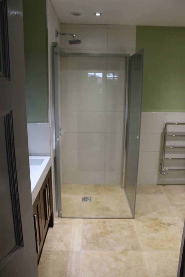Photo of a large contemporary ensuite bathroom in Dorset with freestanding cabinets, medium wood cabinets, a freestanding bath, a corner shower, a one-piece toilet, white tiles, ceramic tiles, white walls, travertine flooring and a vessel sink.