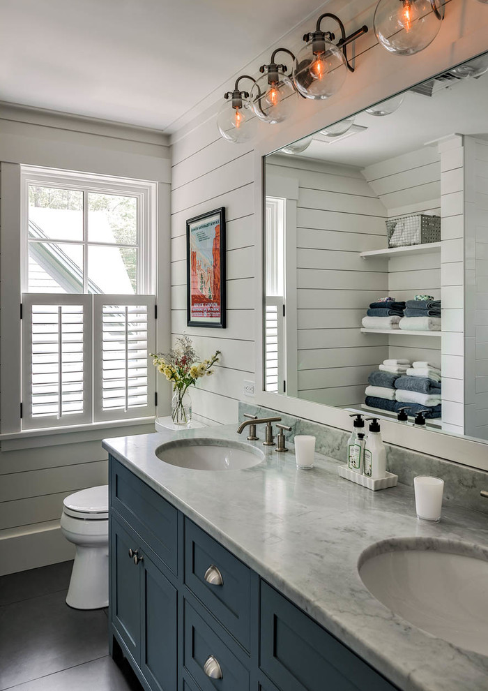 На фото: ванная комната в морском стиле с фасадами в стиле шейкер, синими фасадами, белыми стенами, врезной раковиной, мраморной столешницей, черным полом, серой столешницей и окном с
