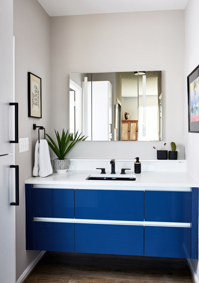 Cette photo montre une salle d'eau chic de taille moyenne avec un placard à porte plane, des portes de placard bleues, un mur gris, un lavabo encastré, un sol marron, un plan de toilette blanc, meuble simple vasque et meuble-lavabo suspendu.