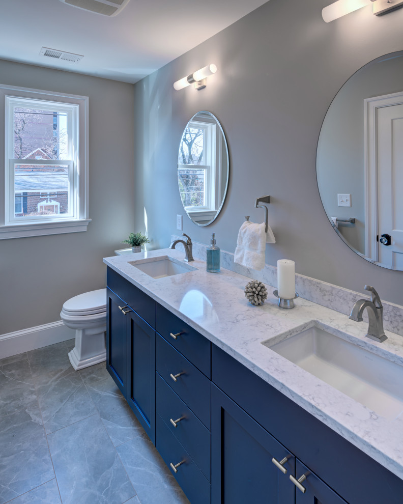 На фото: главная ванная комната среднего размера в стиле неоклассика (современная классика) с фасадами в стиле шейкер, синими фасадами, душем в нише, унитазом-моноблоком, синей плиткой, керамической плиткой, белыми стенами, полом из керамогранита, врезной раковиной, столешницей из искусственного кварца, серым полом, душем с распашными дверями, белой столешницей, сиденьем для душа, тумбой под две раковины и напольной тумбой