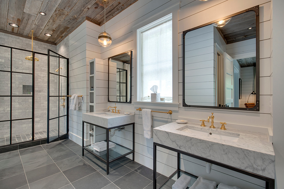 Cette image montre une salle de bain principale rustique avec un carrelage gris, un mur blanc, une vasque, un plan de toilette en marbre et une cabine de douche à porte battante.
