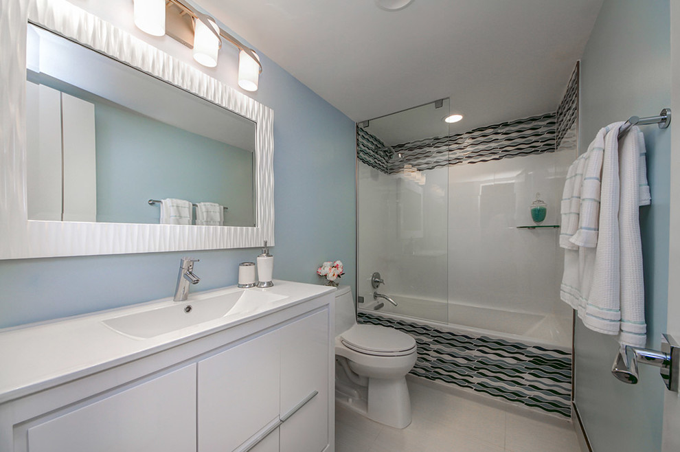 Kleines Modernes Badezimmer En Suite mit verzierten Schränken, weißen Schränken, Einbaubadewanne, Duschbadewanne, Toilette mit Aufsatzspülkasten, blauen Fliesen, Glasfliesen, blauer Wandfarbe, Porzellan-Bodenfliesen, Einbauwaschbecken, grauem Boden und offener Dusche in Miami
