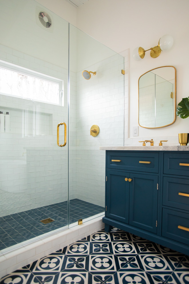 Photo of a medium sized ensuite bathroom in Los Angeles with shaker cabinets, blue cabinets, a freestanding bath, a walk-in shower, a one-piece toilet, white tiles, metro tiles, white walls, ceramic flooring, a submerged sink, marble worktops, blue floors, a hinged door and grey worktops.