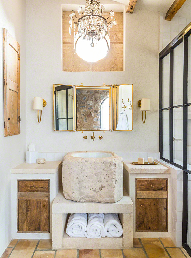 Diseño de cuarto de baño mediterráneo con armarios con paneles lisos, puertas de armario con efecto envejecido, baldosas y/o azulejos blancos, paredes blancas, lavabo sobreencimera y suelo naranja