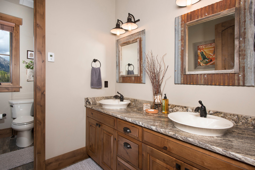This is an example of a rustic ensuite bathroom in Denver with beaded cabinets, light wood cabinets, beige walls, dark hardwood flooring, a vessel sink, granite worktops and brown floors.