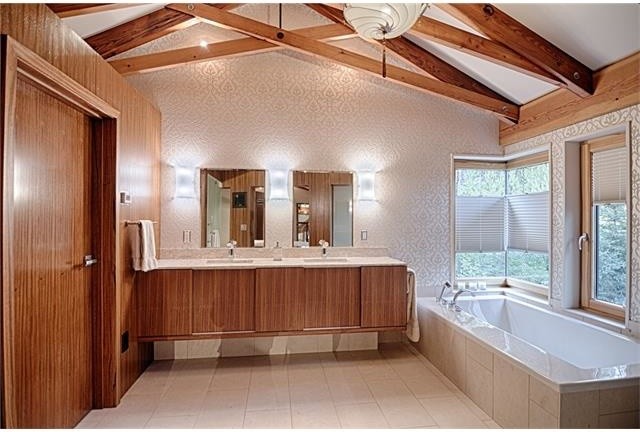 Inspiration pour une grande salle de bain principale minimaliste en bois brun avec un placard à porte plane, une baignoire encastrée, un carrelage blanc, un carrelage en pâte de verre, un mur beige, un sol en carrelage de porcelaine, un lavabo encastré, un plan de toilette en calcaire et un sol beige.