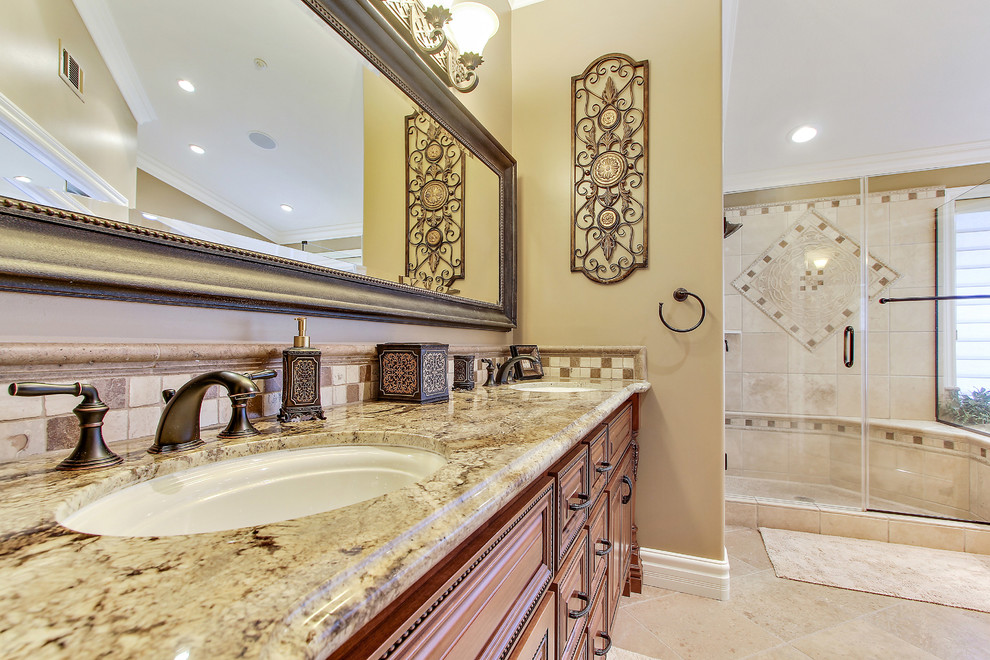 Idées déco pour une grande salle de bain principale classique en bois brun avec un placard avec porte à panneau surélevé, une baignoire d'angle, une douche double, un carrelage beige, du carrelage en travertin, un mur beige, un sol en marbre, un lavabo encastré et un plan de toilette en granite.