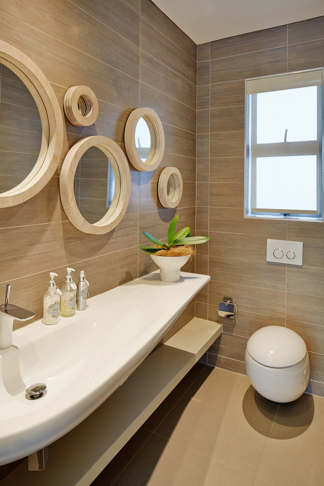 他の地域にあるコンテンポラリースタイルのおしゃれな浴室 (壁付け型シンク、オープンシェルフ、一体型トイレ	、ベージュのタイル、ベージュの壁) の写真