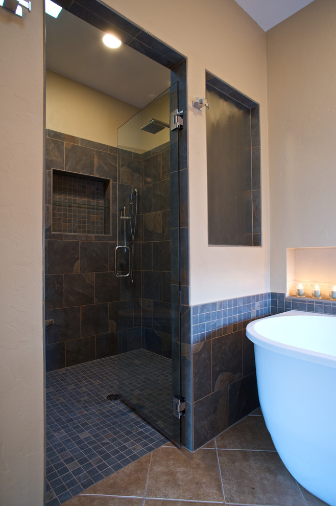 Cette photo montre une salle de bain principale chic avec une baignoire indépendante, une douche à l'italienne, un carrelage gris, un carrelage de pierre, un mur beige et un sol en ardoise.