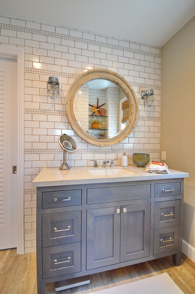 Esempio di una stanza da bagno costiera con ante in stile shaker, ante grigie, piastrelle bianche, pareti beige, lavabo sottopiano, pavimento marrone e top bianco