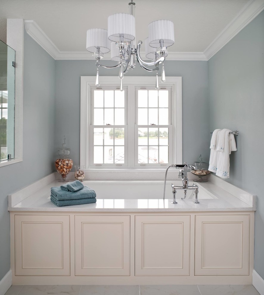 Inspiration pour une salle de bain traditionnelle avec une baignoire encastrée, un carrelage blanc et un mur bleu.