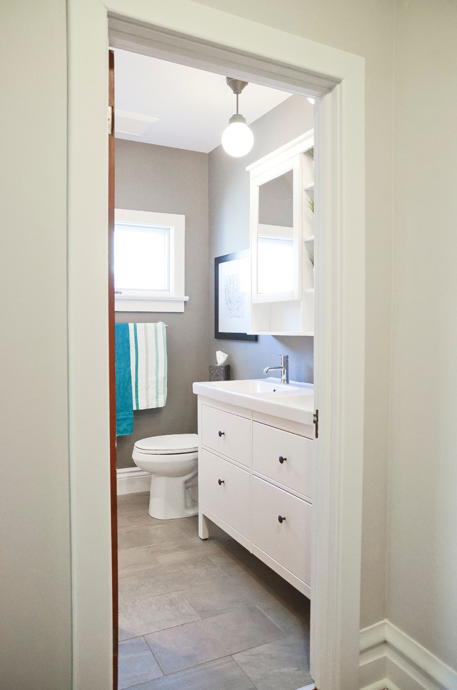 Cette image montre une salle de bain avec des portes de placard blanches, un carrelage blanc, des carreaux de porcelaine, un mur gris, un sol en carrelage de porcelaine et un lavabo intégré.