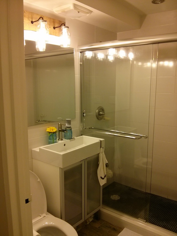 Diseño de cuarto de baño principal actual pequeño con lavabo tipo consola, armarios tipo vitrina, sanitario de una pieza, baldosas y/o azulejos de cerámica y paredes blancas