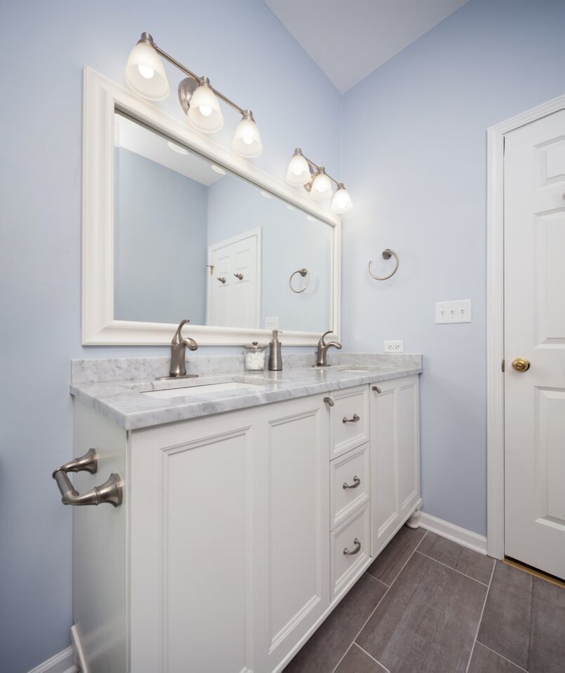 Bild på ett stort vintage badrum med dusch, med ett undermonterad handfat, luckor med profilerade fronter, vita skåp, marmorbänkskiva, en dusch i en alkov, en toalettstol med separat cisternkåpa, vit kakel, keramikplattor, blå väggar och klinkergolv i keramik