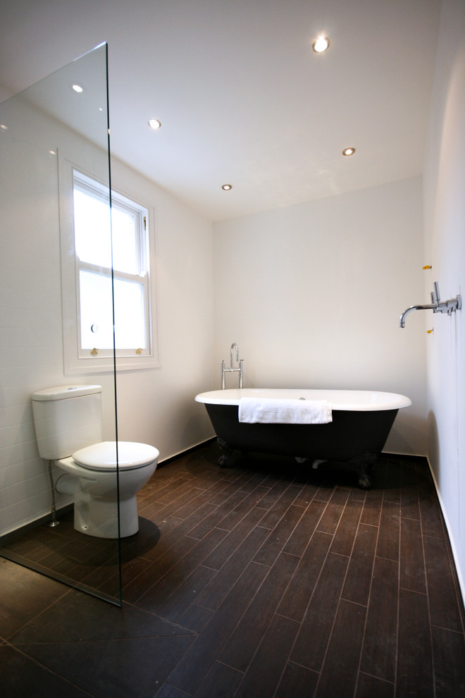 Cette image montre une salle de bain traditionnelle de taille moyenne pour enfant avec une baignoire indépendante, une douche à l'italienne, WC suspendus, un carrelage noir et un mur noir.